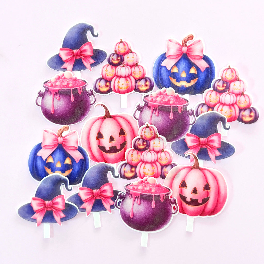 A set of Halloween-themed paper cupcake toppers on a white background, featuring pink and blue jack-o'-lanterns, witch hats with pink bows, and purple cauldrons with dripping pink candy. Edible Wafer Card Cupcake Toppers - Pink Halloween