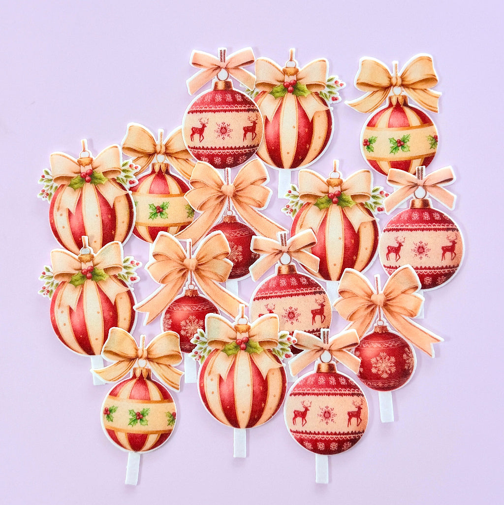 A set of Christmas ornament-shaped picks or decorations arranged on a light lavender background. Each ornament has a red and cream striped body with festive patterns like reindeer, snowflakes, holly, and bows in warm beige tones. Edible Wafer Card Cupcake Toppers - Christmas Baubles